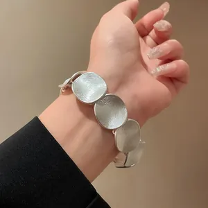Nahaufnahme eines minimalistischen silbernen Armbands mit runden Scheiben und Textur