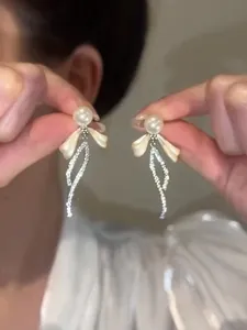 Dettaglio di eleganti orecchini a perno a fiocco con perle e strass
