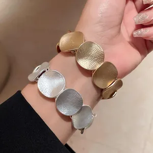 Nahaufnahme von stilvollen gold- und silberfarbenen Hammerschlag-Metallarmbändern
