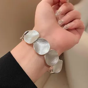 Nahaufnahme eines minimalistischen, silbernen, strukturierten Gliederarmbands am Handgelenk
