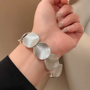 Detailansicht eines modischen runden silbernen Armbands mit Struktur an einem Handgelenk