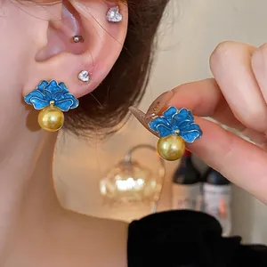 Eleganti orecchini a fiore vintage con perle, petali in smalto blu e perni dorati.
