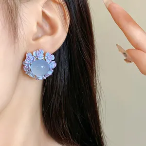 Detailed close-up of a sweet floral resin stud earring featuring a blue center stone on an ear