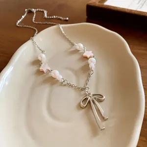 Close-up detail of the elegant bow pendant featuring pink star and white pearl accents.