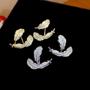 Detailed macro view of gold and silver feather earrings with pavé cubic zirconia.