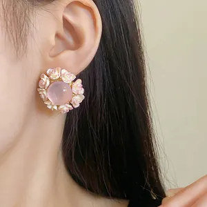 Detail view of pink flower resin stud earrings worn on ear for women