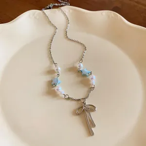 Close-up of elegant silver necklace with bow pendant, delicate pearls and blue stars