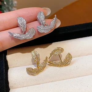 Detailed view of 18k gold-plated leaf stud earrings with sparkling zircon stones.