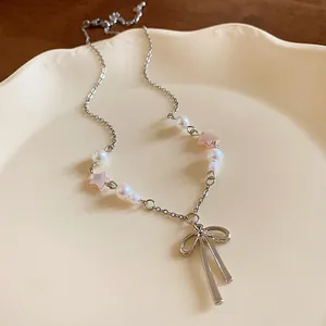 Close-up detail of a silver bow pendant necklace featuring pink stars and white pearls