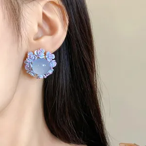 Close-up detail of a purple floral resin stud earring with a translucent center