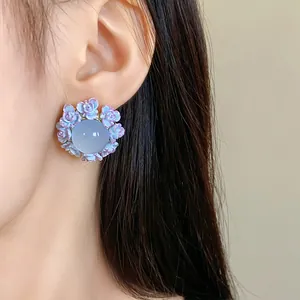 Detailed view of sweet floral resin stud earrings with a blue central stone