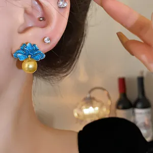 Dettaglio orecchini vintage a fiore smaltato blu con perla dorata su modella.