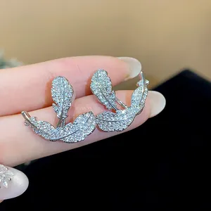 Macro detail of exquisite feather stud earrings with sparkling clear zircon stones