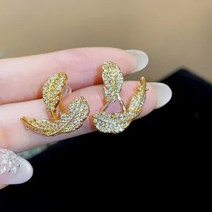 Macro detail of 18k gold plated feather earrings with sparkling cubic zirconia stones