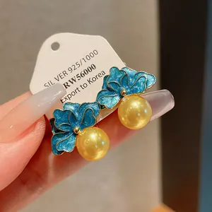 Dettaglio ravvicinato di orecchini vintage a fiore smaltato blu con perle gialle