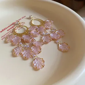 Close-up of elegant pink petal drop earrings with zircon studs and white pearl accents
