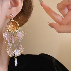 Detail of elegant pink petal dangle earrings with pearls and zircon worn by a model.