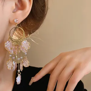 Detailed shot of elegant pink petal earrings with zircons and pearls on delicate gold chains