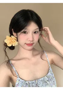 Giovane donna asiatica con una grande clip per capelli a fiore giallo 3D sui capelli