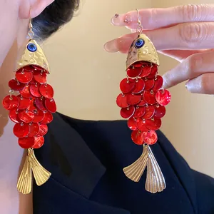 Detail macro view of red koi fish earrings with shell scales and blue evil eye detail