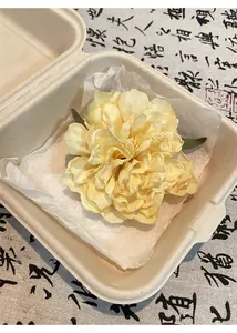 Elegante fermaglio per capelli con fiori gialli in una confezione regalo beige rustica.