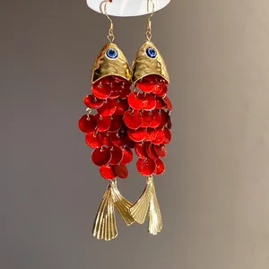 Macro detail shot of koi fish drop earrings featuring red sequins and golden fish tail