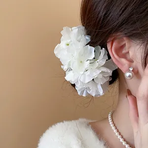 Elegant white fabric flower hair pin worn on a side bun for a soft feminine style