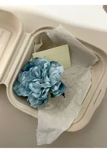 Primo piano di un elegante fermaglio per capelli a fiore 3D blu in confezione ecologica