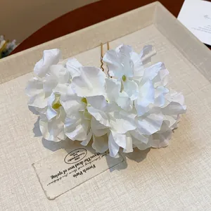 Close-up detail of white fabric flower hair pin with U-shaped gold metal fork.