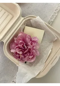 Primo piano di un fermaglio per capelli a forma di fiore rosa in scatola ecologica.