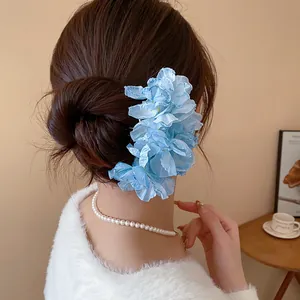 Close-up view of an elegant blue fabric flower hair fork accessory worn in a stylish bun