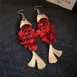 Close-up detail of koi fish dangle earrings with red sequins and gold metallic finish