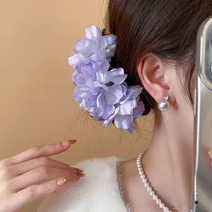 Detailed side view of an elegant purple fabric flower hair fork worn by a model
