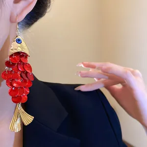 Detailed macro view of a red sequin koi fish tassel earring on a model's ear.
