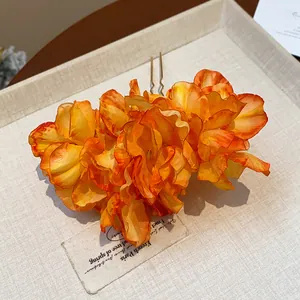 Detailed macro view of vibrant orange fabric flower petals on an elegant metal hair fork