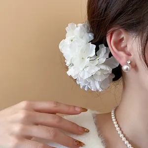 Elegant white fabric flower hair pins shown in a close-up detail on model's hair