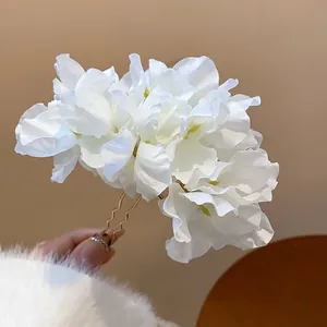 Close-up detail showing elegant layers of white fabric flowers on a gold-tone metal hair fork