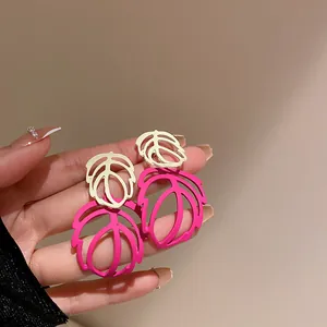 Stylish pink and cream monstera leaf dangle earrings shown held in hand for display