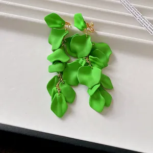 Detail view of vibrant green wrinkled petal tassels on elegant gold chain clip-on earrings.