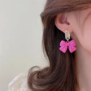 Elegant pink bow earrings with clear rhinestones shown on a model for fashion