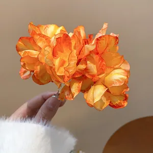 Close-up of a vibrant orange layered fabric flower hair fork with delicate petal texture.