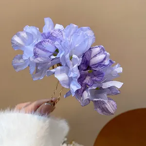 Detail of purple fabric flower hair fork with elegant multi-layered petals held by hand