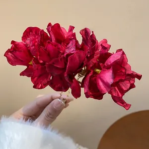 Detailed macro view of elegant burgundy fabric flower hair fork with gold-tone base
