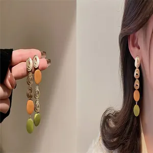 Detail of multi-colored long drop earrings with gold textured and matte circles