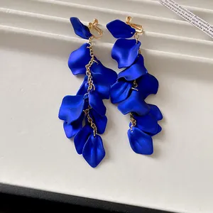 Close-up of cobalt blue pleated petal tassel earrings on a white display base