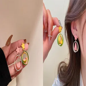 Detailed view of colorful star and double circle earrings worn by a model