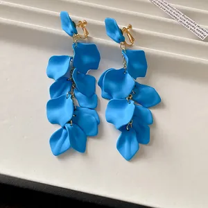 Close-up of vibrant blue matte petal tassel clip-on earrings displayed on a white tray