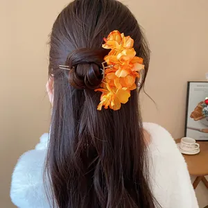 Close-up detail of a sweet orange fabric flower hair pin elegantly styled in a bun