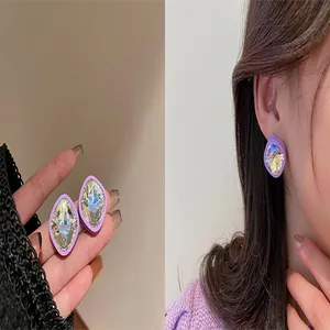 Detailed view of purple square faceted crystal stud earrings on an Asian model's ear.