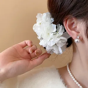 Elegant white fabric flower hair fork shown worn in hair for a dreamy styling look